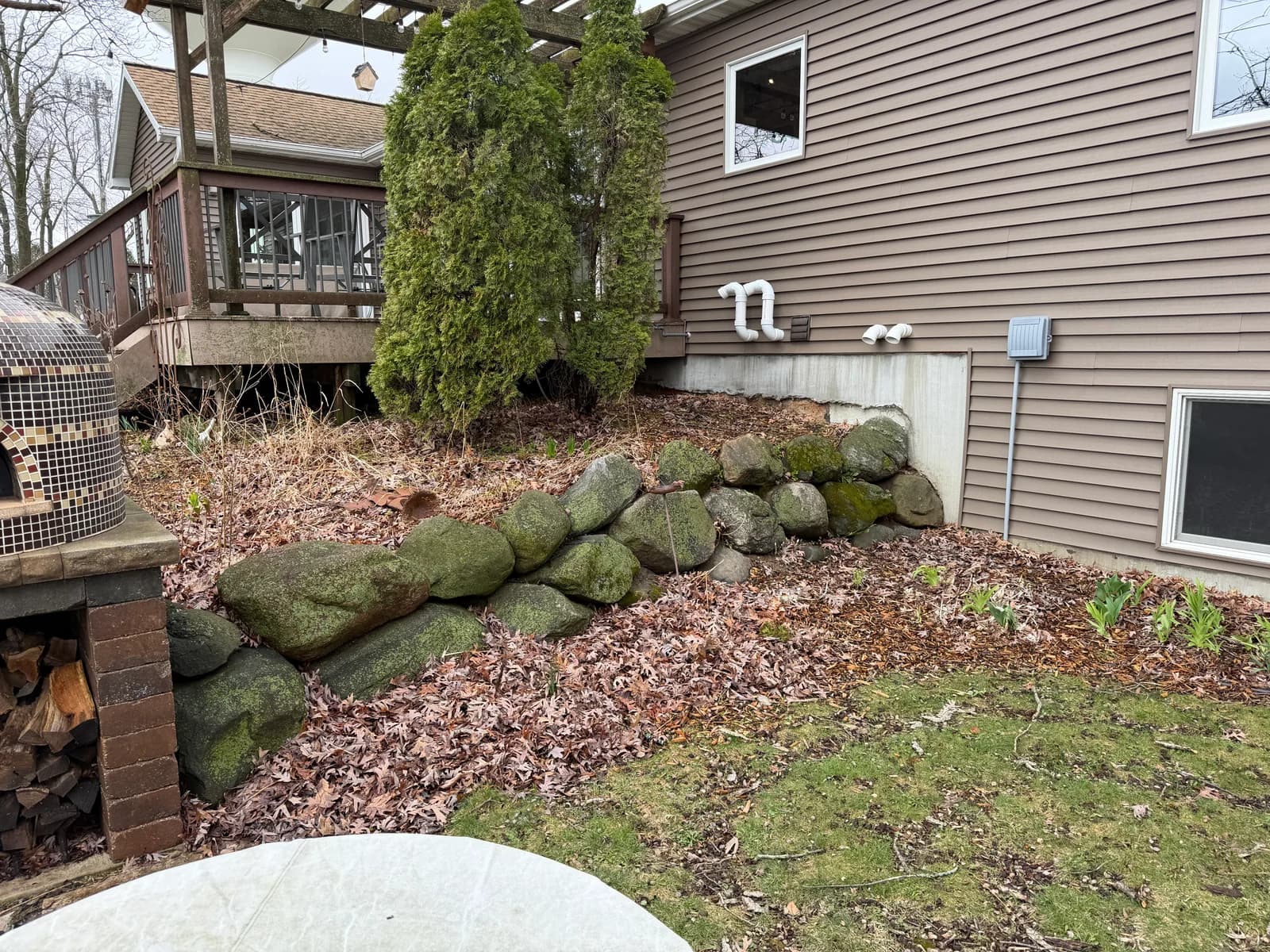 Rock wall area covered in dead leaves and winter debris